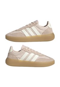 Zapatillas deportivas beige con parte superior de ante y sintético, tres rayas blancas y suela de goma translúcida. Punta redondeada y diseño de cordones.