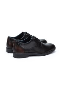 Chaussures en cuir noir avec une finition lisse et des accents marron, dotées d'un design à lacets, d'un bout rond et d'une semelle en caoutchouc basse.