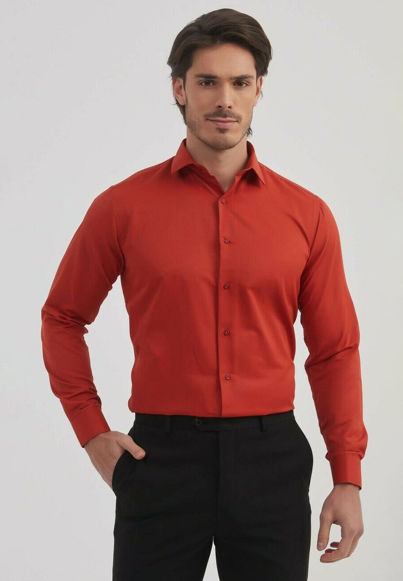 Chemise rouge à manches longues en tissu lisse avec un col boutonné et des boutons sur le devant, associée à un pantalon noir. Design simple et ajusté.