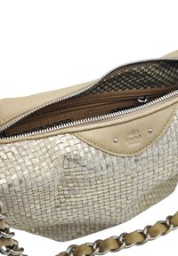 Sac à main beige avec une texture métallique tissée, une fermeture éclair et un intérieur à motifs. Dispose d'une bandoulière en chaîne et en cuir.