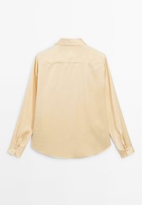 Helles beige Langarmhemd aus glattem Stoff, mit spitzem Kragen, knöpfbaren Manschetten und einem abgerundeten Saum in einem klaren Design.