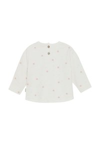 Witte langmouwige shirt met een knoopsluiting op de rug, voorzien van verspreide roze en blauwe bloemenpatronen op een zachte stof.