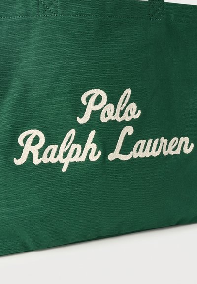 Πράσινη υφασμάτινη τσάντα tote με λευκή κεντημένη επιγραφή «Polo Ralph Lauren» στο κέντρο της πλευράς.