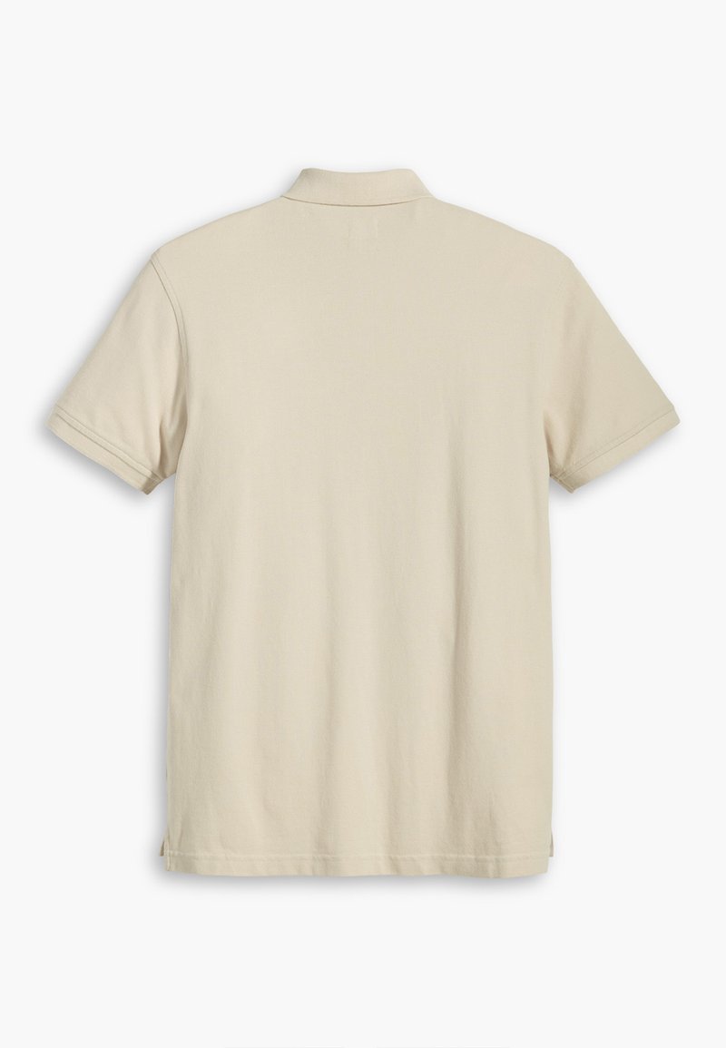 Camisa polo de algodón beige, de mangas cortas, con cuello clásico, diseño liso, presenta aberturas laterales en el dobladillo para mayor comodidad en el movimiento.