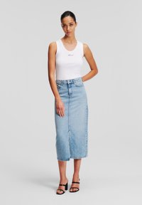 Bela majica na naramenice z vezenim napisom, v kombinaciji z svetlo modrimi denim midi krili s sprednjo odprtino. Črne sandale s peto dopolnjujejo obleko.