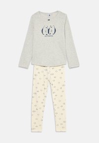 Gray long-sleeve top with two navy blue penguin illustrations and "Petit Bateau" text, paired with cream leggings patterned with small penguins.