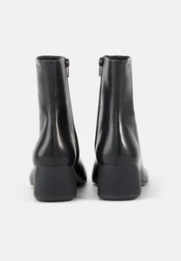 Black leather ankle boots with a smooth texture, zip closure, and chunky heel. Minimalistic design with a rounded toe and polished finish.