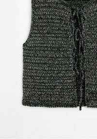 Czarna i srebrna dzianinowa kamizelka z teksturowanym prążkowanym wzorem, z przodu z zapięciem na sznurek i bez rękawów. Materiał wydaje się miękki i przytulny.