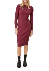 Abito in maglia a coste bordeaux con maniche lunghe, silhouette aderente, lunghezza al ginocchio, abbinato a stivaletti neri per creare contrasto. Texture liscia.