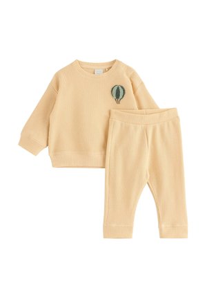 Beige langærmet top i vaffelstrik med et lille grønt luftballonpatch og matchende bukser, designet til småbørn.