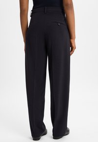 Zwarte, high-waisted broek met een wijde pijpdesign. Bevat een enkele achterzak met een knoop, op maat gemaakte stof en een strakke afwerking.