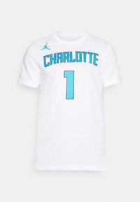 Camiseta de algodón blanca con la palabra "CHARLOTTE" en letras aqua en negrita y el número "1" abajo. Incluye un pequeño logo Jumpman aqua en el hombro.