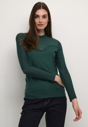 Top de manga larga en tela verde oscuro, con cuello alto y una textura suave, presenta un detalle de diseño curvado en el pecho.