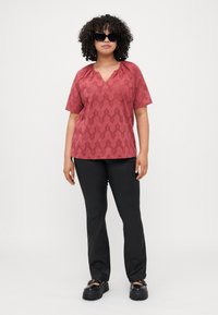 Top corto di colore lampone a maniche corte con scollatura a V, caratterizzato da un motivo a zigzag testurizzato. Abbinato a pantaloni neri a gamba dritta e scarpe nere chunky.