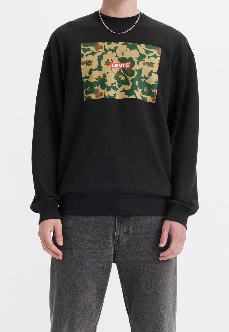 Felpa nera con un motivo camouflage in verde e beige, con un logo rosso "LEVI'S" ben visibile. Realizzata in un tessuto morbido e con maniche lunghe.