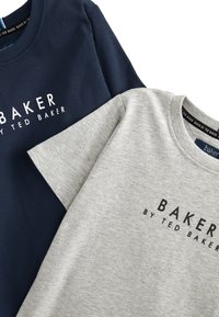 Jūras zila un pelēka kokvilnas T-krekli ar apaļām kakla izgriezumiem, īsām piedurknēm un priekšējo apdruku ar tekstu "BAKER BY TED BAKER." Mīksta tekstūra, ikdienišķs dizains.
