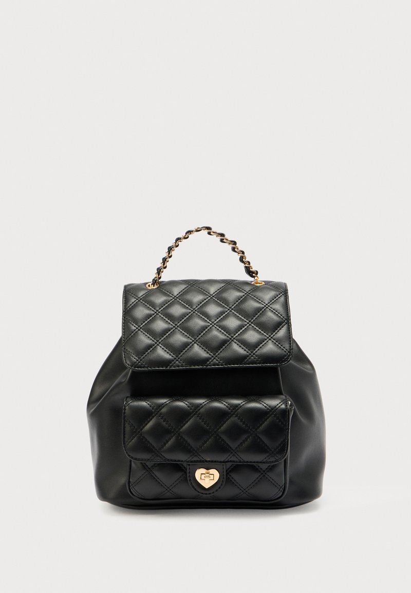 Sac à dos en cuir noir matelassé avec une poignée chaîne dorée, une poche à rabat avant, une fermeture en forme de cœur et une texture lisse.