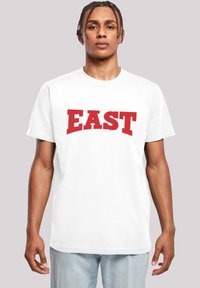 Bílý bavlněný tričko s výrazným červeným nápisem "EAST". Kulatý výstřih, krátké rukávy, pohodlný střih. Hladká textura, minimalistický styl.