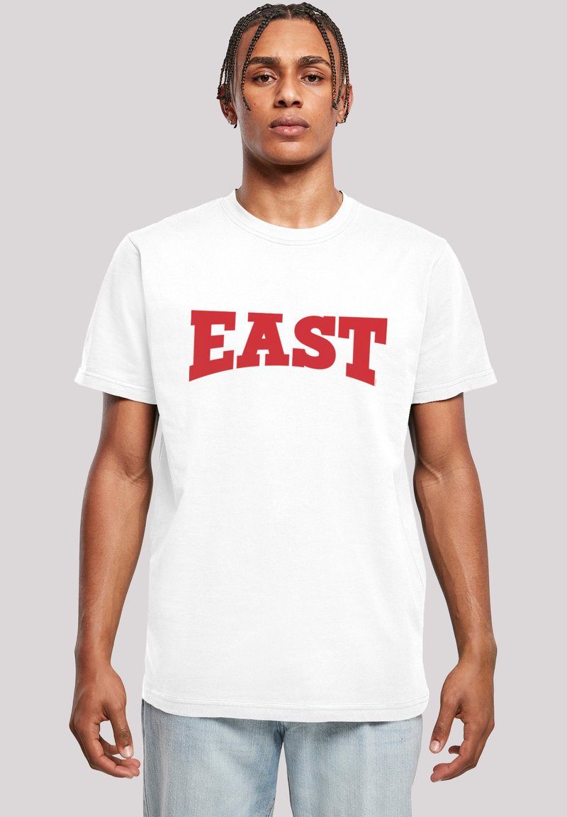 Bílý bavlněný tričko s výrazným červeným nápisem "EAST". Kulatý výstřih, krátké rukávy, pohodlný střih. Hladká textura, minimalistický styl.