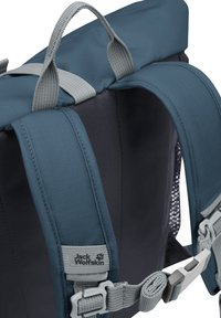 Zaino con tessuto teal, spallacci grigi e una maniglia superiore. Presenta un pannello in rete, fibbie regolabili e un'etichetta con logo sul lato.