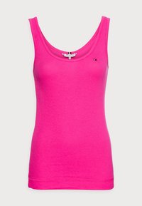 Top sin mangas de color rosa, hecho de algodón suave, con un escote redondo y una pequeña etiqueta de logo en la parte delantera izquierda. Textura suave, diseño ajustado.