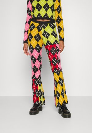 Calças flare tricotadas com um padrão argyle ousado, apresentando cores rosa, vermelho, amarelo, verde e preto. Acabamento texturizado com calçado preto.