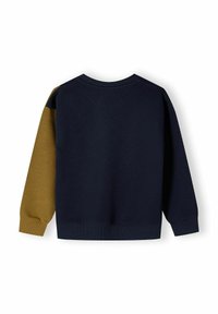 Marinblå sweatshirt med en senapsgul ärm, ribbade muddar och nederkant, med rund halsringning och mjukt material.