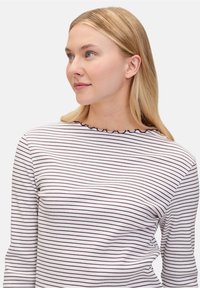 Gestreiftes Langarmshirt mit weißem Grund und dünnen dunkelvioletten Streifen. Verfügt über eine gerippte Textur und einen Rüschenausschnitt.