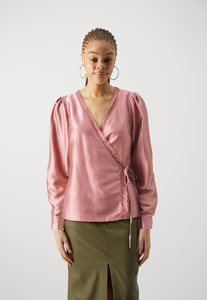 Rosa Satin-Wickelbluse mit vertikalen Streifen und Spitzenbesatz. Mit langen Puffärmeln und einer Bindeverschluss an der Taille.