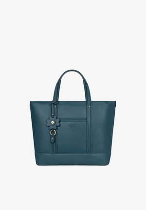 Turchese leren tote bag met dubbele handvatten, voorzak en een bloemvormige leren sleutelhanger als decoratie.