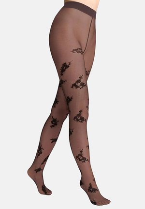 Nogi w przezroczystych czarnych rajstopach w kwiatowy wzór z nieprzezroczystym paskiem, ustawione na jasnym, jednolitym tle.