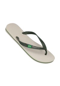 Chanclas con tiras verdes y suela texturizada en color crema, presentando un acento de logo y un borde verde a lo largo del filo. Estilo de tira estándar.