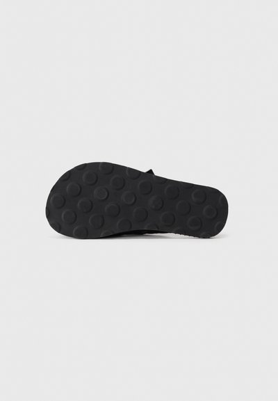 Black sandal sole with circular tread patterns, displayed flat on a white background.