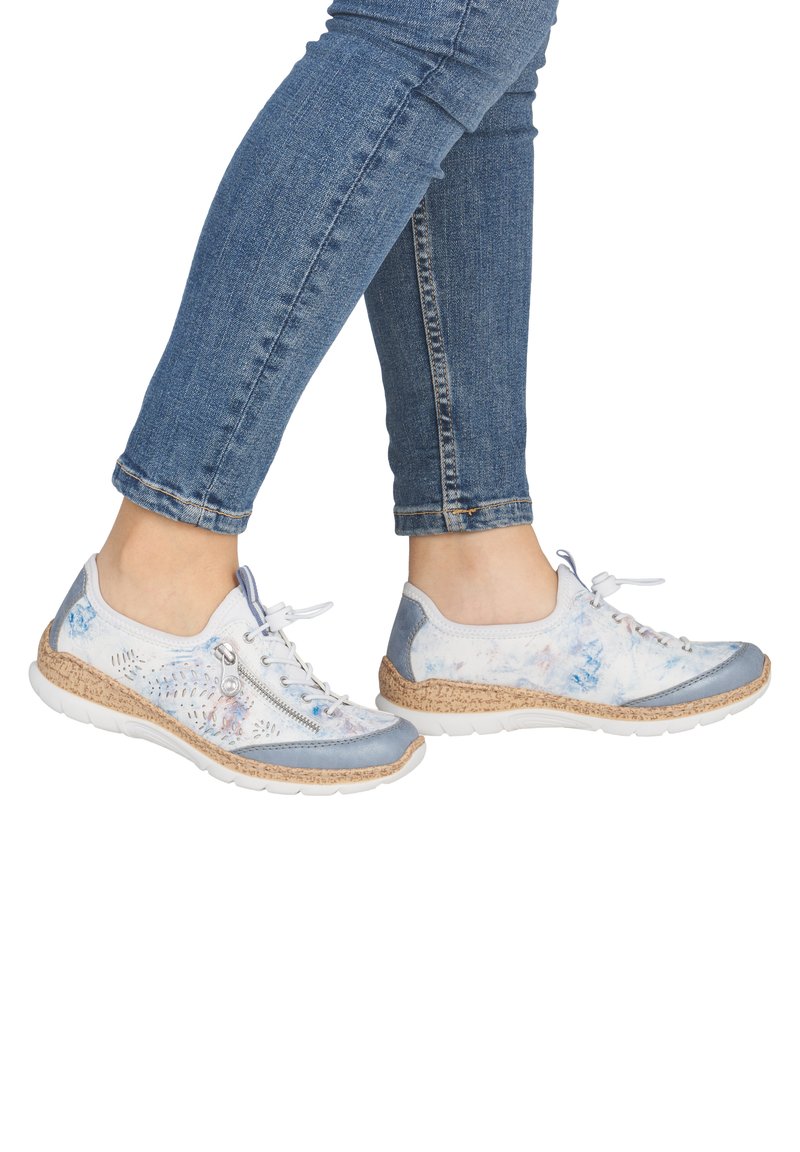 Les baskets légères présentent un design en matériaux mixtes avec des accents bleus, des motifs floraux, et une semelle intermédiaire en liège texturée. Fermeture à lacets avec une fermeture éclair latérale.