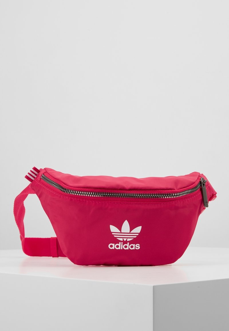 Rosa ryggsäck med en slät nylonfinish, med en zippered stängning, justerbar rem och vit Adidas-logotyp på framsidan.