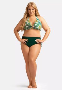 Dwuczęściowy strój kąpielowy: top na halter z zielono-białym wzorem liści, akcent w formie otworu; spodenki w kolorze jednolitym, wysokiej talii w odcieniu zielonym. Gładka tekstura tkaniny.