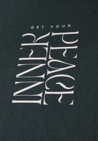 T-shirt vert foncé avec un texte vertical blanc : "OBTENEZ VOTRE PAIX INTÉRIEURE" avec divers styles et tailles de police sur un tissu doux.
