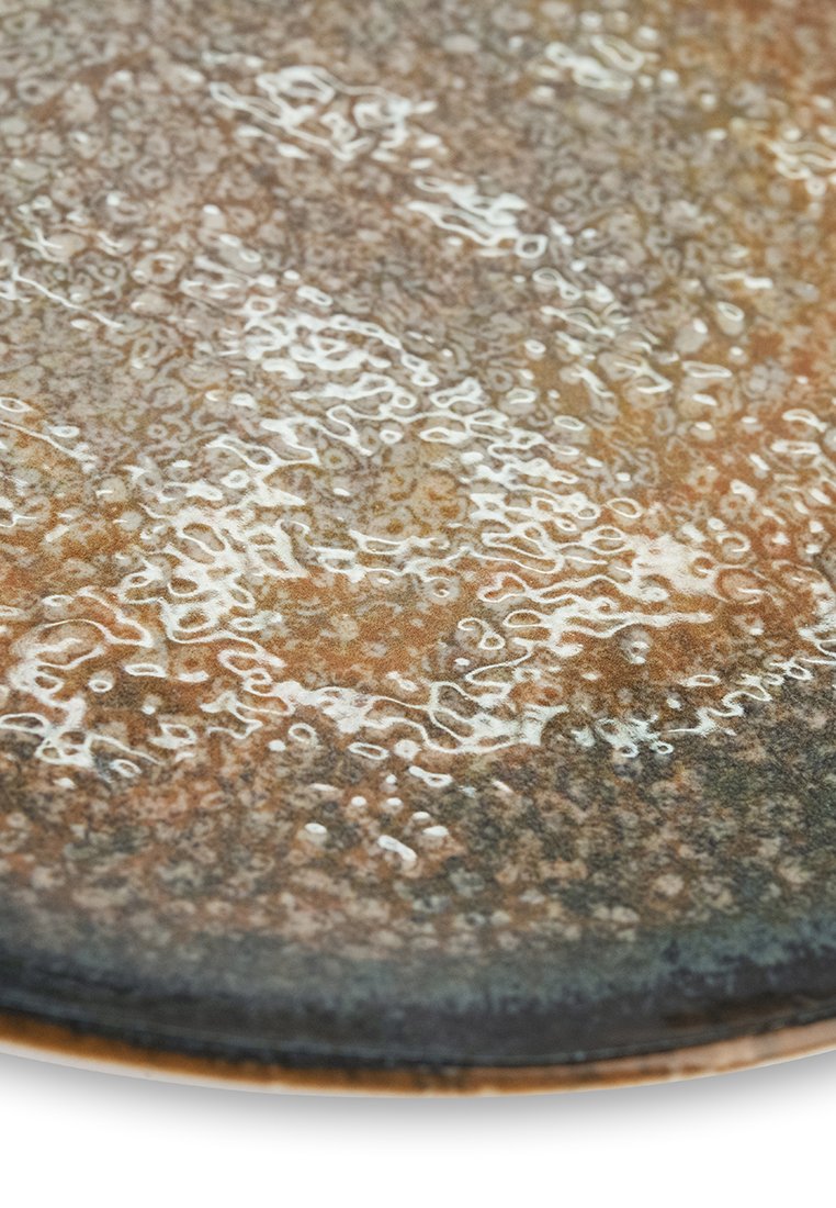 Runde Keramikteller mit strukturierter Oberfläche, in einer Mischung aus erdigen Brauntönen, dezenten Weißtönen und einem dunklen Rand. Auffällige glänzende Oberfläche.