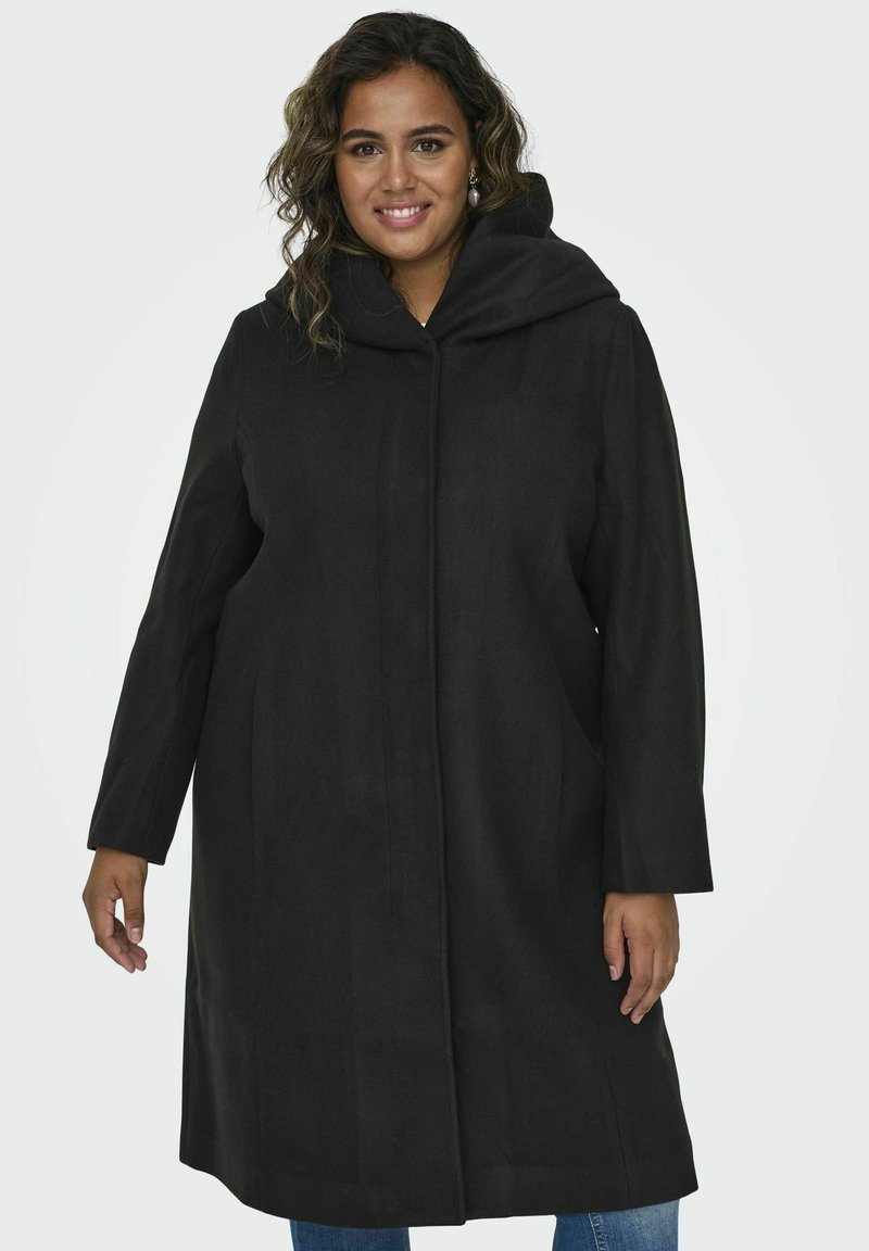 Manteau noir à capuche avec une silhouette droite, des manches longues et des poches latérales, fabriqué dans un tissu lisse au fini mat.