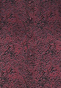 Teksturowana tkanina z czerwono-czarnym wzorem przypominającym nieregularne plamy lub komórki, o gładkim wykończeniu i miękkim wyglądzie.