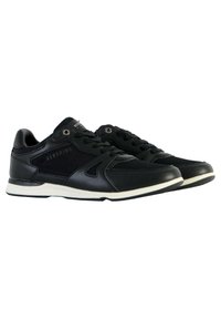 Scarpe sportive nere con tomaia in pelle liscia, dettagli in rete, suola bianca e lacci neri. Presentano un marchio sui lati e sulla linguetta.