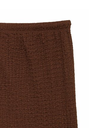 Jupe en tissu marron texturé avec une taille élastique, montrant un motif tricoté détaillé et une coupe droite.