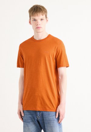 Blandet oransje kortermet t-skjorte laget av myk stoff, med rund hals og liten "BOSS" logo på venstre bryst. Brukt med blå jeans.