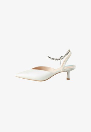Chaussure slingback blanche avec un bout pointu et un petit talon de type kitten. Dotée d'un accent en chaîne autour de la cheville. Texture lisse et mate.