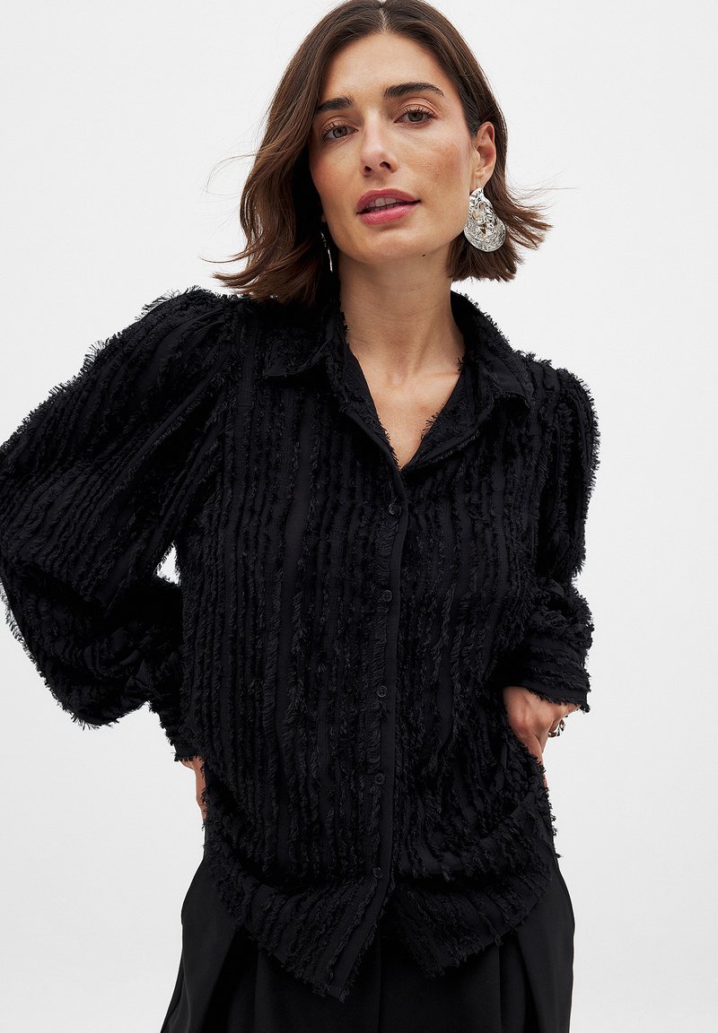 Black button-up shirt with textured, frayed stripes; features a collar and loose, long sleeves; made of soft, lightweight fabric.