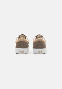 Scarpe in suede marroni e beige con suole in gomma bianche, caratterizzate da un design semplice e cuciture visibili sul tallone e sugli accenti laterali.