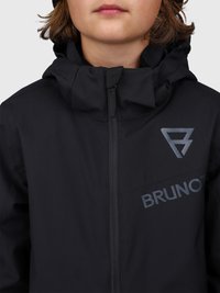 Kadar izbliza osobe u crnoj jakni s patentnim zatvaračem i visokim ovratnikom, s logom "BRUNOTTI" na prsima.