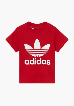 Camiseta roja de manga corta para niños pequeños con logo blanco de Adidas trefoil y texto centrado en la parte delantera.