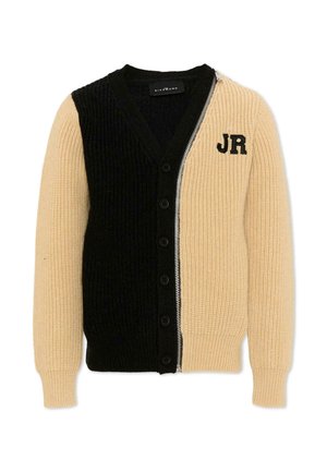 Beige en zwarte geribbelde gebreide cardigan met knopen aan de voorkant aan de zwarte zijde en rits aan de beige zijde, met zwarte "JR" letters op de borst.
