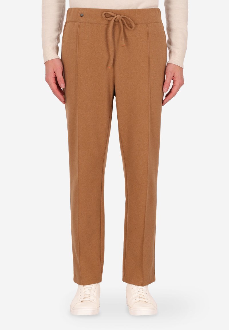 Pantaloni in maglia marrone con vita regolabile, caratterizzati da dettagli sulle cuciture laterali e un fit rilassato, abbinati a sneaker bianche.